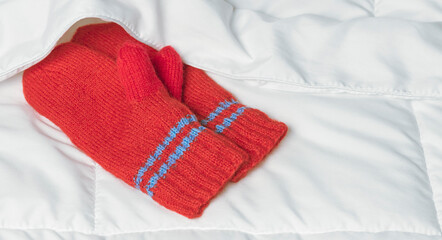 Red mittens under white blanket. The warmth of home comfort.