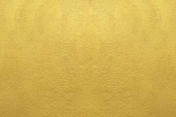 Gold wall texture background. Yellow shiny gold paint on concrete wall surface