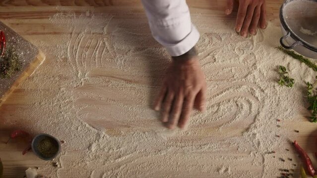 Chef hand preparing flour on wooden cutting board in food restaurant kitchen.