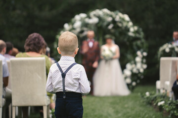 A little boy carries wedding rings for the bride and groom