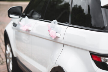 Wedding decor on the car handle. Flower decoration with ribbons on a white car