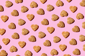 Heart shaped Oatmeal cookies, top view on trendy pink  background. Creative Pattern made of cookies. Repeating Oatmeal cookies pattern. Flat lay style.