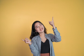 asian young woman pointing fingers up while standing