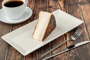 Fototapeta premium Sliced san sebastian cheesecake with coffee on wooden table