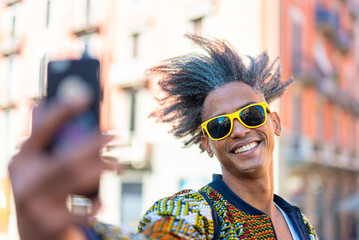 african american stilish man looking at the smartphone, influencer creating contents for social media, selfie time of a weird haired african guy