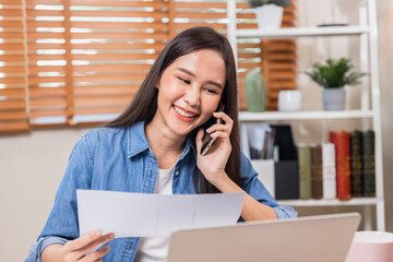 Beautiful Asian woman working and talking on phone at home