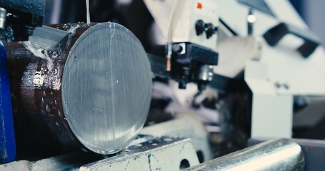 The automatic band saw machine cutting the metal rod. The machine tool operation with liquid coolant.