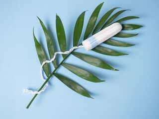 Clean white cotton swabs on a blue background on a green leaf. Feminine hygiene during...