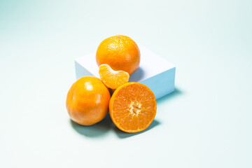 Whole tangerines and tangerines in a close-up section on a light blue background in natural light.