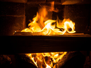 Burning firewood in a fireplace in a country house. Rustic stove with burning logs close-up.