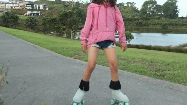 portrait of young child or teen girl roller skating outdoors, fitness, wellbeing, active healthy lifestyle. 