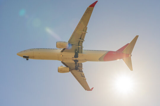 Looking up underneath a large jet as in flies past the Sun in a blue sky