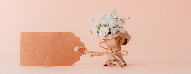 miniature bouquet of gypsophila is wrapped in kraft paper with an empty tag. Greeting card