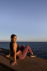 Woman sitting by the sea at sunset