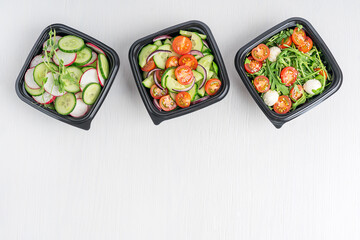 Top view of different vegetarian vegetable salads made of cucumber slices, arugula and tomatoes...