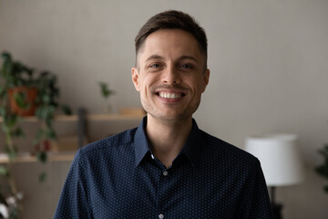 Head shot portrait of happy young 30s Hispanic man showing whitening smile, satisfied with professional dentistry services. joyful confident male homeowner looking at camera, posing in own dwelling.