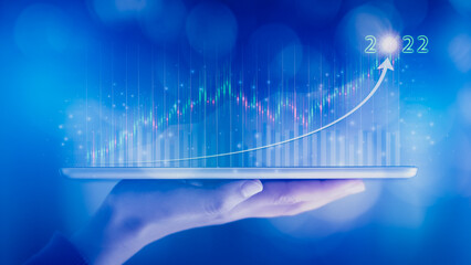 Woman hand showing virtual hologram stock from tablet,2022 business growth concept,Stock market graph or forex trading chart,Planning and strategy,Progress or success,Digital asset,Trader or investor.