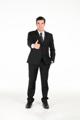 Portrait of a smiling western business man wearing a black suit with thumbs up and his hands in his pants pocket at studio shot on white background.
