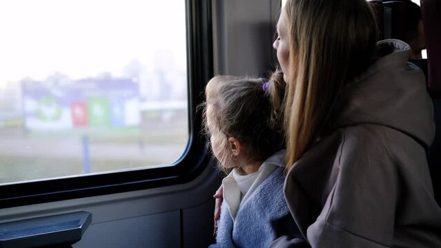 Mom and daughter ride in a train near the window
