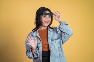 excited asian girl laughing while taking off sunglasses while waving