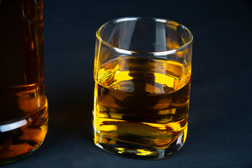A glass of whiskey on the table against a black background