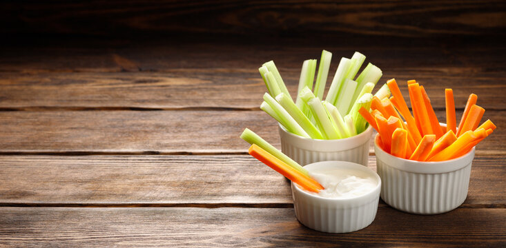 Fresh vegetables - chopped celery sticks and carrots on a wooden background. Diet and healthy food. Copy space for text.