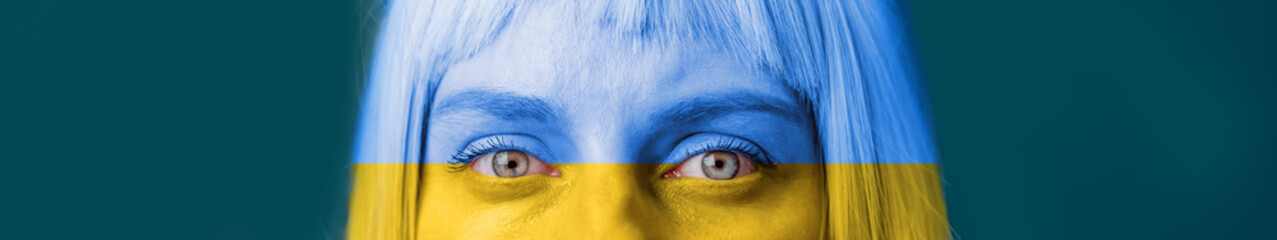 Closeup of a young caucasian woman face in blue yellow ua national colors looking at the camera...