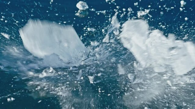 The man breaks piece of ice on the ice. Slow motion. Transparent ice floe is broken on ice with cracks. Shatter to pieces. Frozen Lake Baikal. Winter landscape Natural landmark of Russia. Top view.