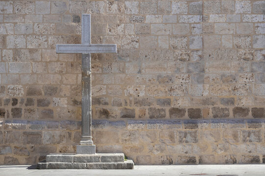 large stone cross in front of a church wall