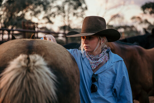 Teenage girl standing beside brown horse