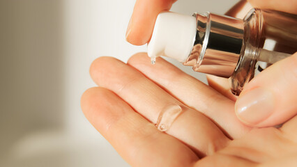 Push dispenser liquid facial fluid gel squeezed out to hand. Cosmetologist pours clear cleansing...