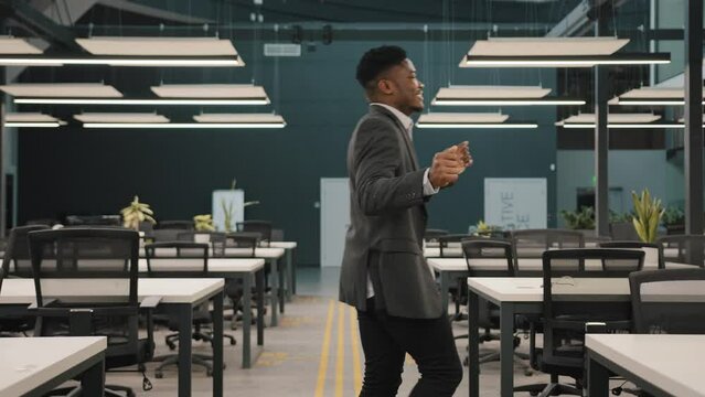 Young man multiracial african employee manager entrepreneur winner dancing alone in modern office satisfied with business success professional achievement motivated male dancer crossing work place