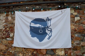 Flag of Corsica, the famous Moors's Head known as Bandera di Corsica, against stone wall.