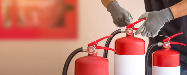 Close up fire extinguisher and firefighter pull safety pin on the handle for protection and prevent...