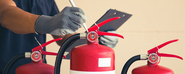 Close up fire extinguisher and firefighter checking pressure gauge level for protection and prevent...
