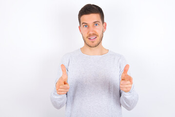 young caucasian man wearing grey sweater over white background directs fingers at camera selects someone. I recommend you. Best choice