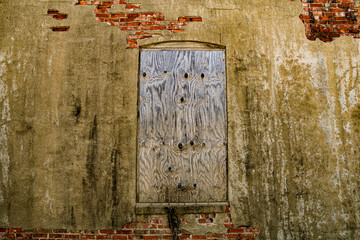 Naklejka premium damaged rural abandoned stucco brick alley wall boarded up window building door closed empty dirty warehouse structure