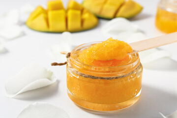 Fototapeta na wymiar Sugar scrub with pieces of ripe mango close-up on a white table.