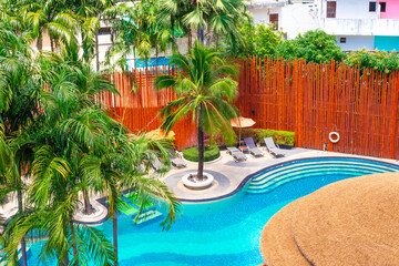 Beautiful swimming pool with palm trees and bamboo fence. Travel and tourism, relaxed vacation