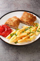 Breaded spanish steak Cachopo served with french fries close-up in a plate on the table. vertical
