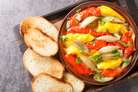 Spanish food Escalivada consists of roasted eggplant, onion and bell peppers with olive oil and minced garlic closeup in the wooden board on the table. Horizontal top view from above