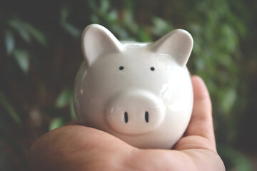 Working man holding piggy bank carefully, saving money for retirement concept.