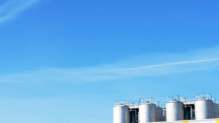 Part of steel tanks of silvery color on a background of the blue sky. Space for text. Winery or petroleum concepts.