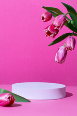 Pink podium for product display on pink with tulips flowers in hard light