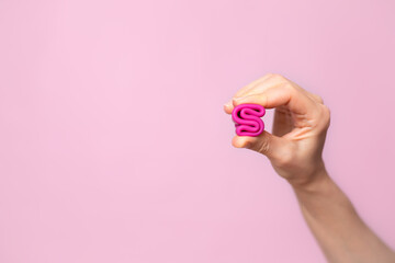 Mature content A young woman folding a pink menstrual cup in her hand. Pink colored background. Space for text. Eco-friendly silicone women's health cycle
