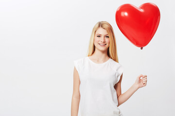 Fototapeta na wymiar Shes got her heart on her sleeve. A gorgeous young blonde woman holding a heart while isolated on a white background.