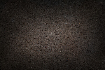 dark textured surface interspersed with small stones and sand