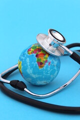  On a blue background lies a mock-up of the earth with a stethoscope with space for text.