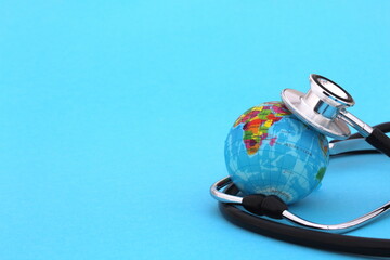 On a blue background lies a mock-up of the earth with a stethoscope with space for text.