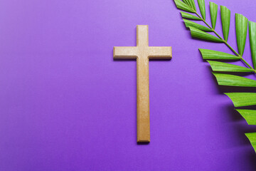 Cross and palm leaves on purple background. Lent season concept.
